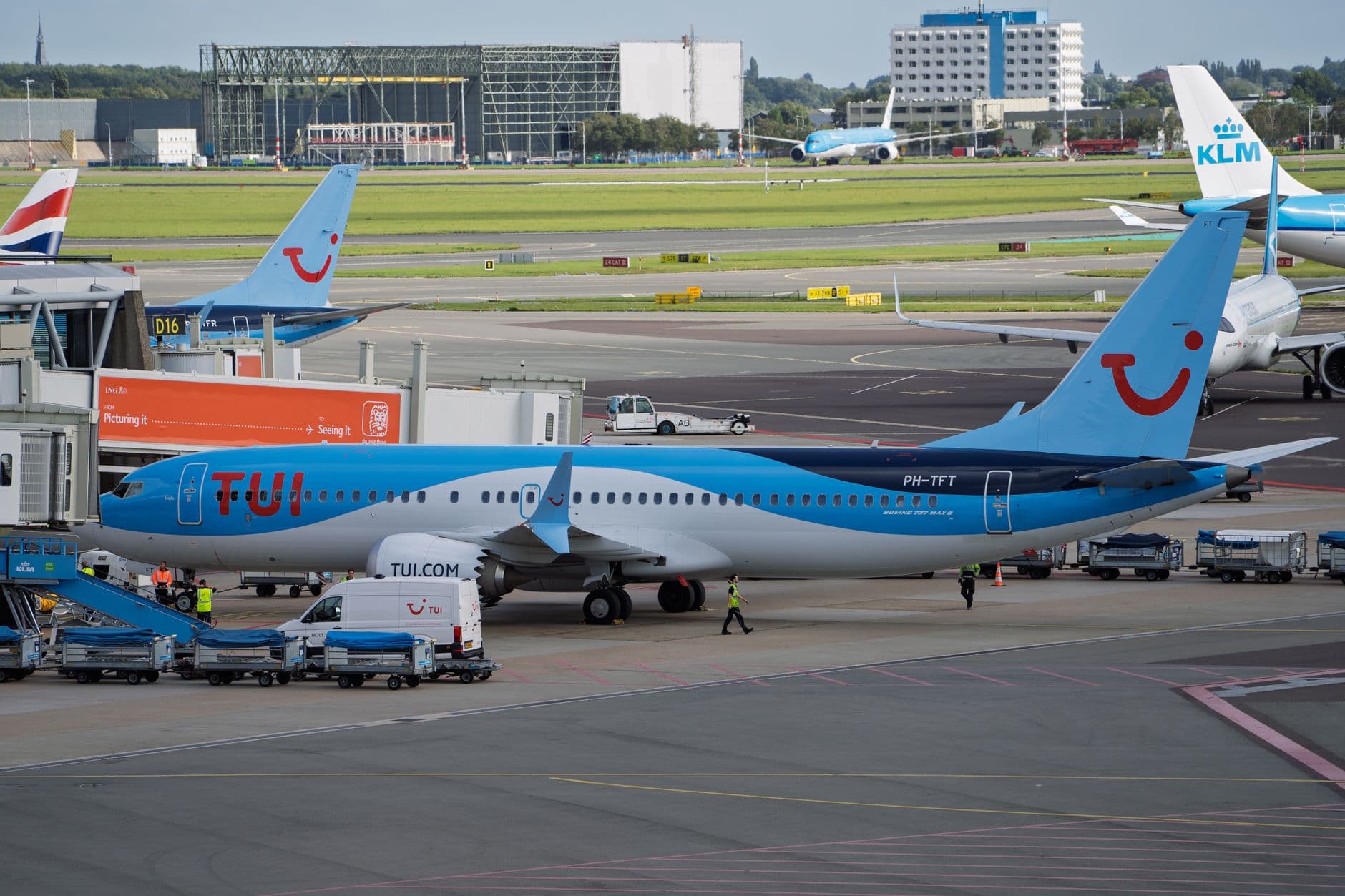TUI aircraft at an airport terminal being prepared for flight on a clear day.