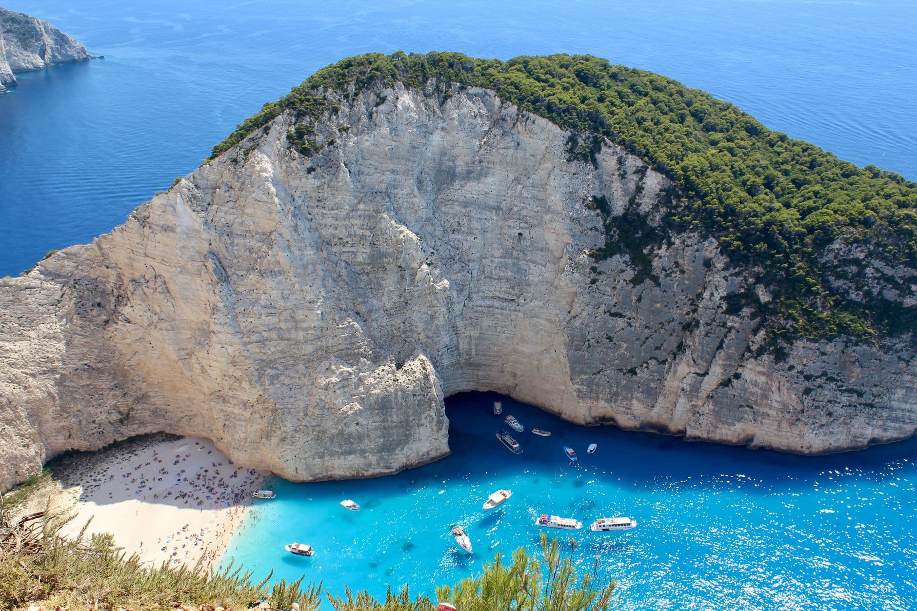 Zicht van bovenaf op het strand van Navagio op Zakynthos, met witte kliffen en bootjes in de baai