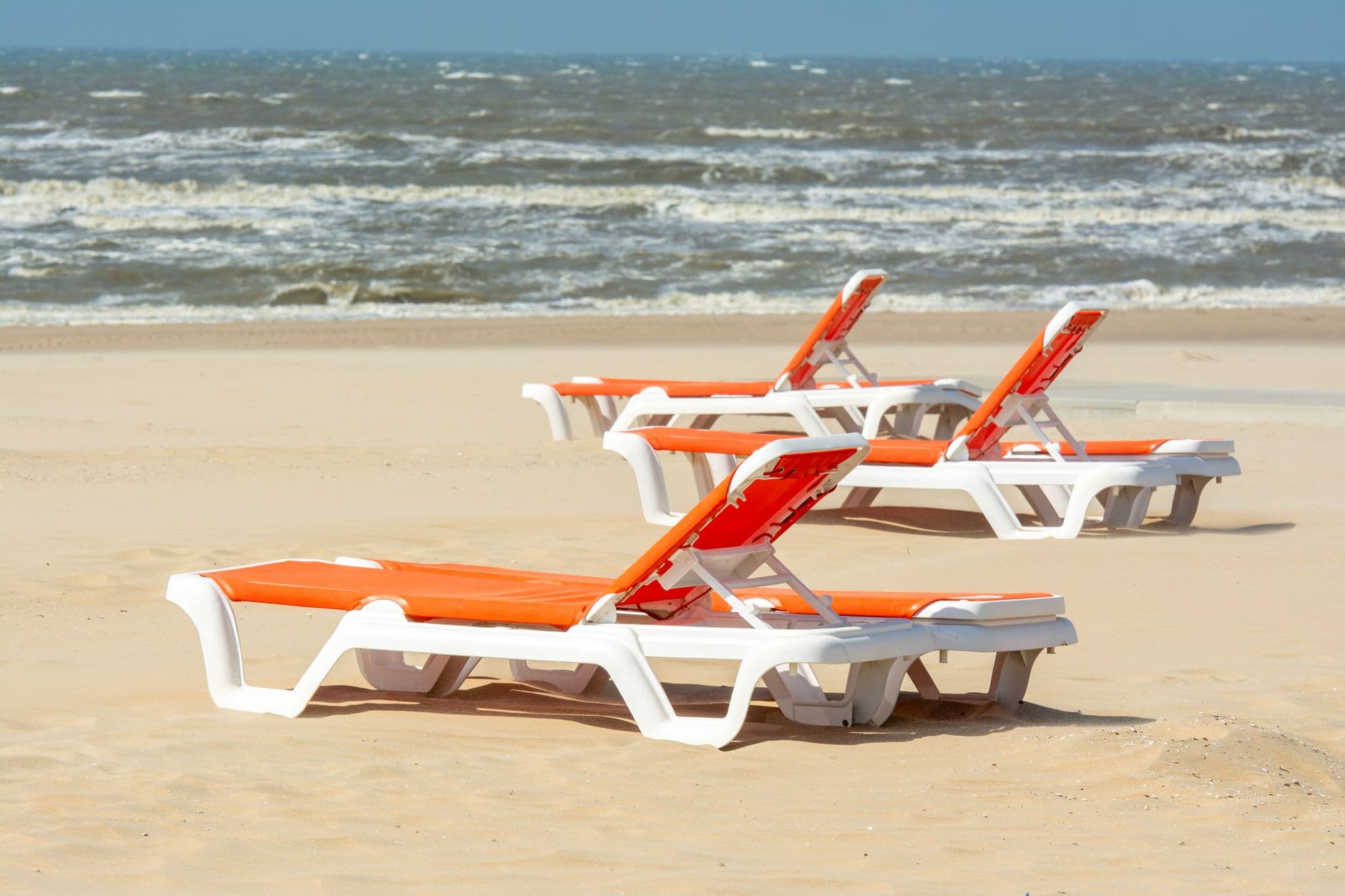 Enjoyable view of sun loungers on a sandy beach with ocean waves in Katwijk aan Zee, Netherlands.
