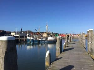 Een ponton van een haven met boten en een staalblauwe hemel in de achtergrond.