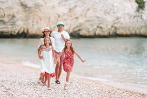 Gezin van vier wandelend langs het strand tijdens de zomervakantie in Italië